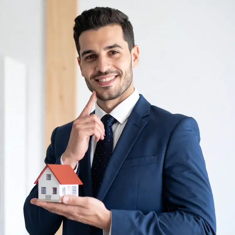 Un homme tient la maquette d'une maison dans sa main, illustrant les secteurs immobilier et BTP concernés par l'assistante de direction freelance